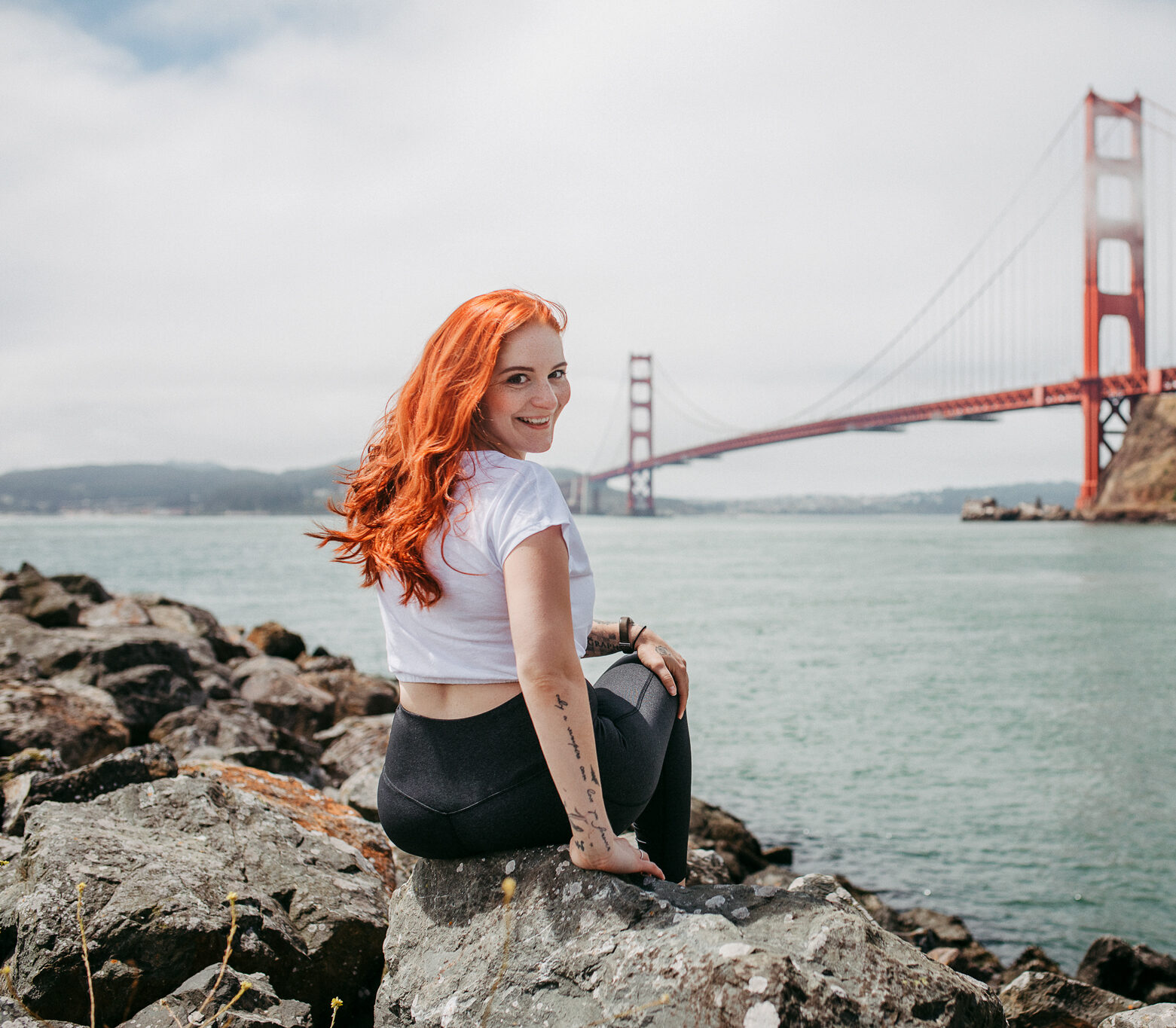 Kim Kärger auf Steinen sitzend vor der roten Brücke von San Francisco, USA.